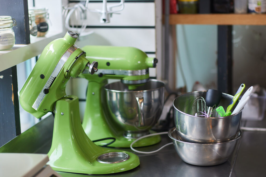 Two green stand mixers with a metal bowl in a kitchen