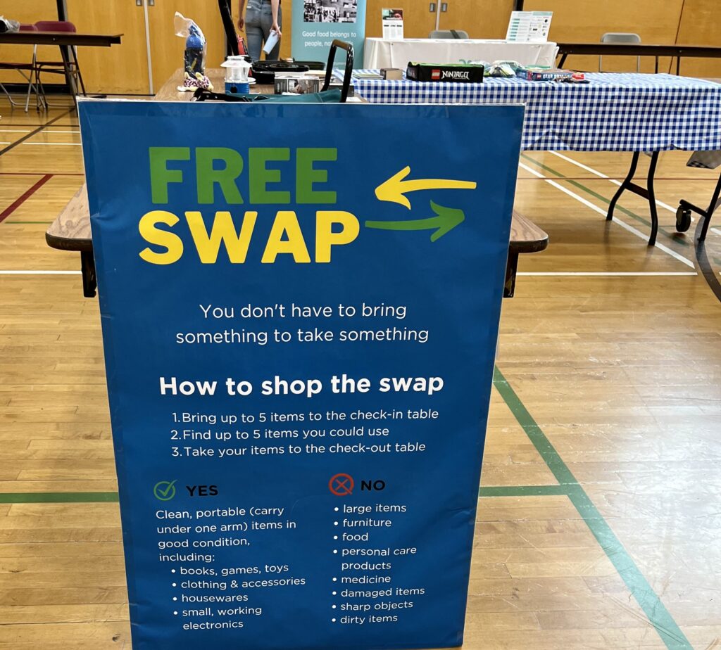 Image of a blue sign that reads: Free Swap. You don't have to bring something to take something. How to shop the swap - 1. Bring up to 5 items to the check-in table. 2. Find up to 5 items you could use. 3. Take your items to the check-out table. Image source: Leah Coulter